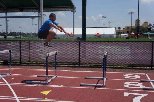 A runner doing a plyometric jump over a hurdle