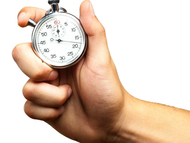 A hand holding a silver stopwatch against a white background, showcasing precision in electronic timing as the second hand approaches the 60-second mark.