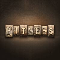 The word FITNESS is spelled out using old, rustic letterpress blocks against a dark, textured background. Each letter is distinct, showcasing a vintage and industrial style.
